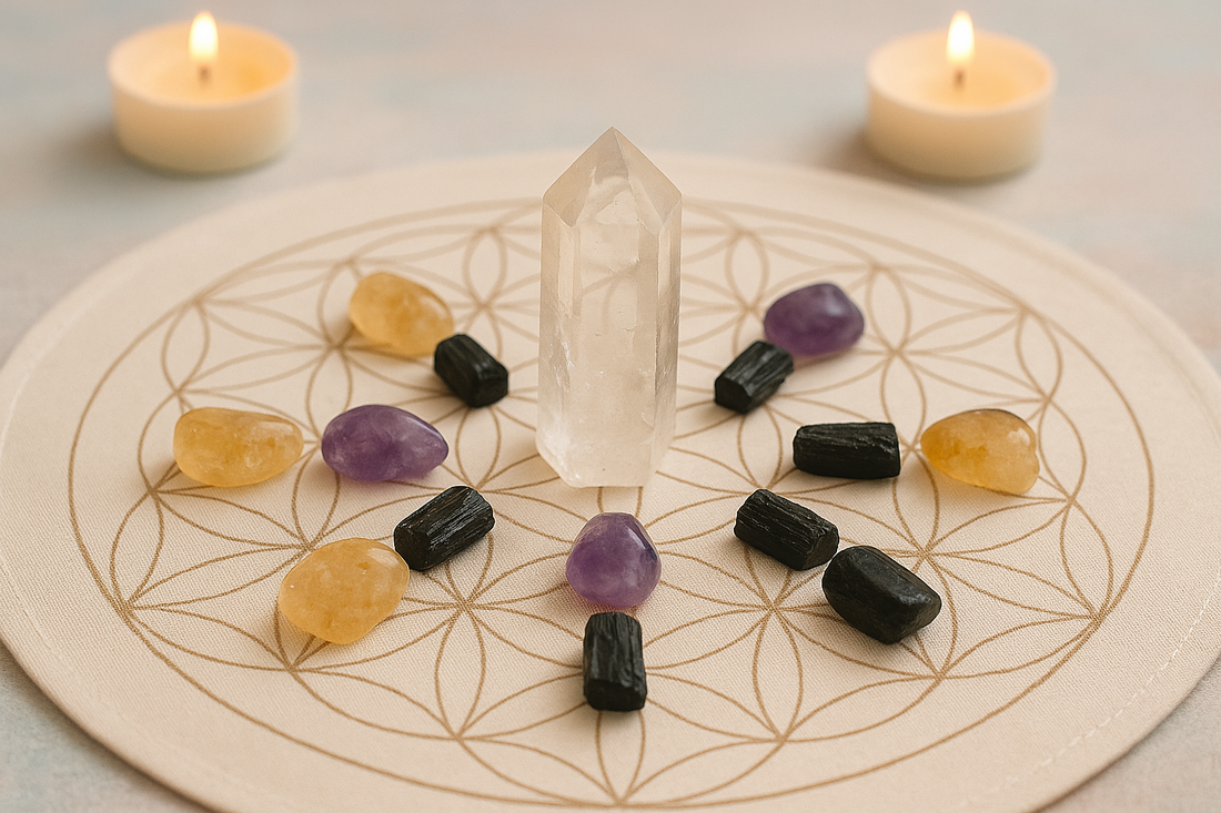 A crystal grid arranged on a flower of life sacred geometry mat, featuring amethyst, citrine, black tourmaline, and a central clear quartz point, with two lit candles in the background.