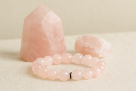 A close-up photograph of a rose quartz beaded bracelet placed on a soft pink background, symbolizing love, healing, and emotional balance.